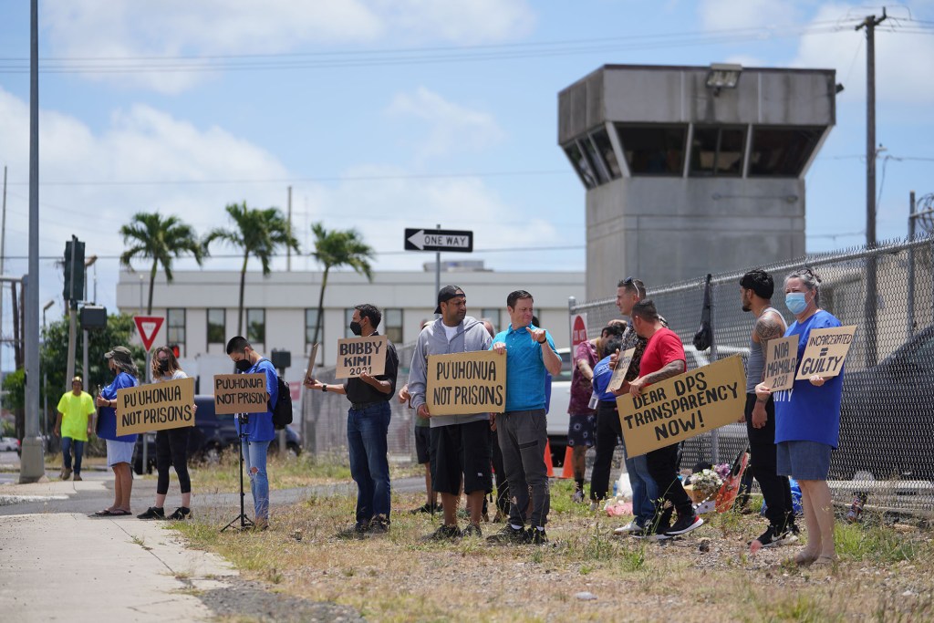 Demonstrators hold signs fronting the OCCC Oahu Community Correctional Center.