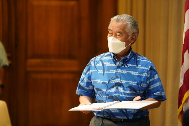Governor David Ige walks into the ceremonial room holding a binder before the intent to veto bills press conference begins.