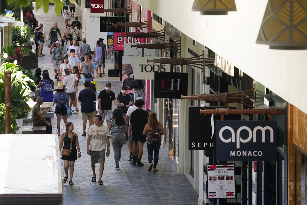 Masked and unmasked people walk along the shops at Ala Moana Shopping Center.