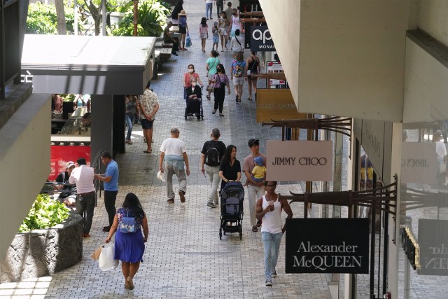 Masked and unmasked people walk along the shops at Ala Moana Shopping Center.