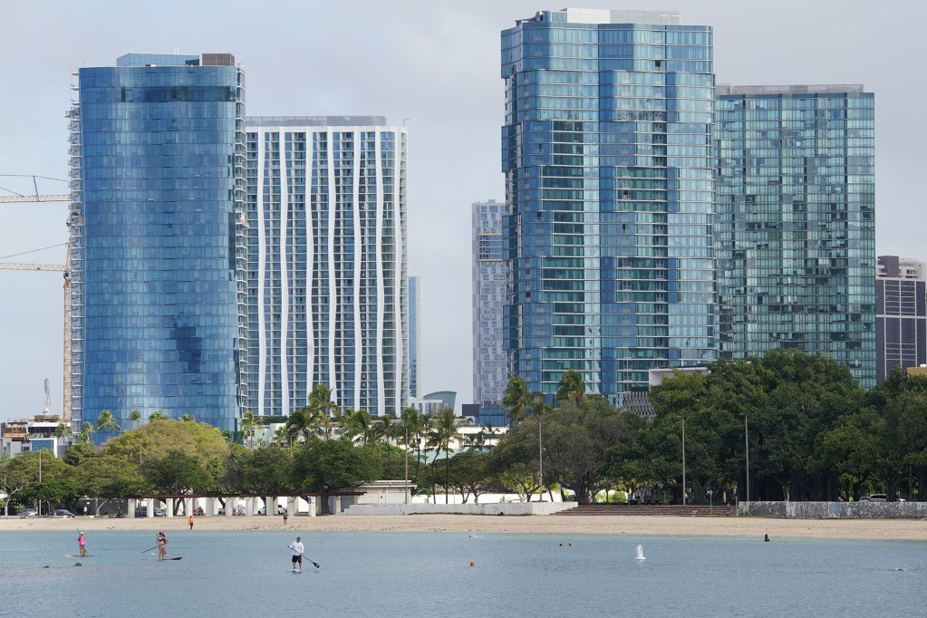Kakaako condominiums tower over paddle boarders enjoying the water at Ala Moana Beach Park.
