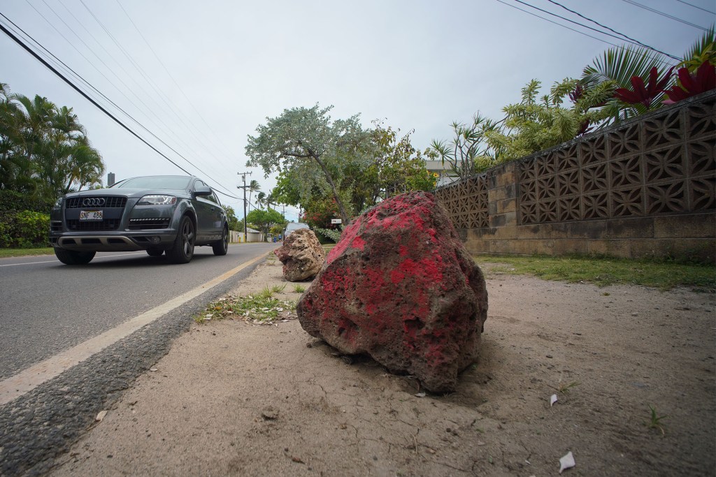 Large rocks painted red placed on the side of Lanikai's Mokulua Drive to deter beachgoers from parking near the residents' driveways.