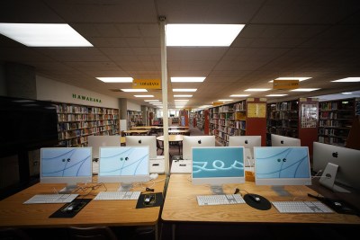 McKinley High School's Daniel Inouye Library located on the second floor of this building.. A view of computers in foreground with many rows of books.