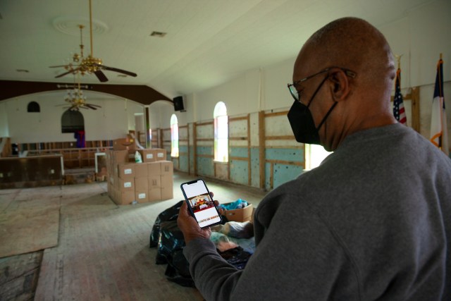 Pastor looks at his phone at the photo of his church before the flood