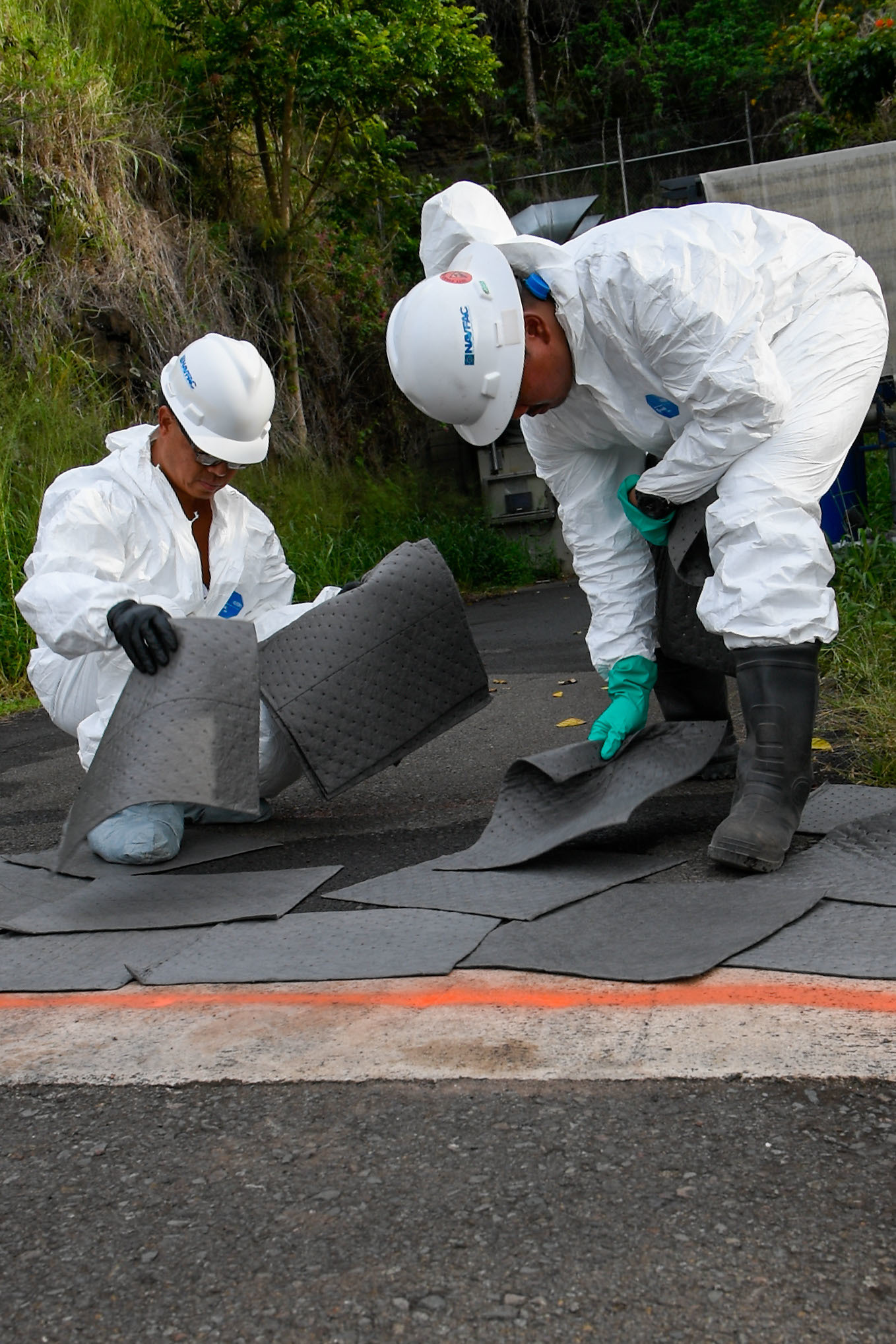 221129-N-FD567-1057 AIEA, Hawaii (Nov. 29, 2022) - Two Naval Facilities Engineering System Command contractors place absorbent mats on an aqueous film-forming foam spill at the Red Hill Bulk Fuel Storage Facility. (U.S. Navy photo by Mass Communication Specialist 3rd Class Christopher Thomas)