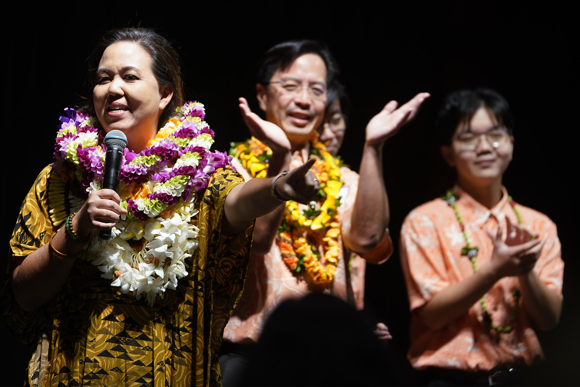 Jill Tokuda gestures while speaking at the Hawaii convention center with her husband and sons.