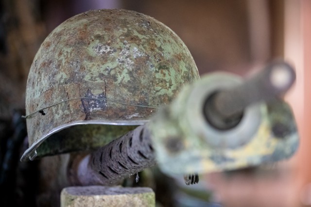 A rusting U.S. Marine helmet sits on top of the remnants of a machine gun