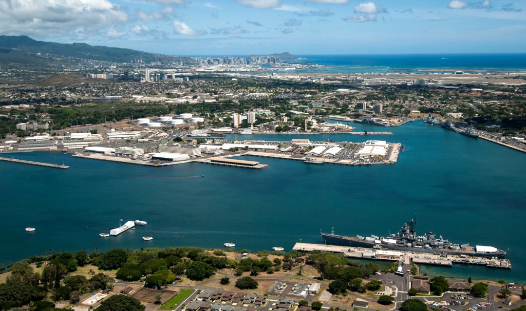 An aerial view of the USS Arizona and USS Missouri Memorials at Ford Island, Joint Base Pearl Harbor-Hickam. Diamond Head, Honolulu and Waikiki are in the distance. (U.S. Navy photo by Mass Communication Specialist Seaman Johans Chavarro/Released)