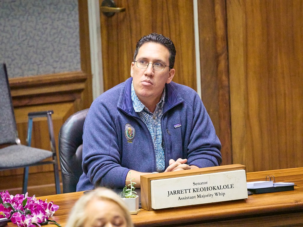 Man in a jacket sits at his desk in the Senate chamber