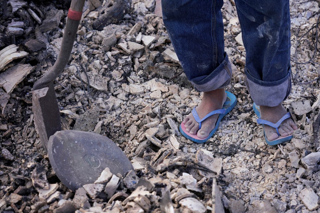 Rolando Bumanglag, 65, only has slippers while he digs for his passport and other important papers Thursday, Aug. 10, 2023, in Lahaina. He thinks it would be in this area of his large house because his room was on the second floor. (Kevin Fujii/Civil Beat/2023)