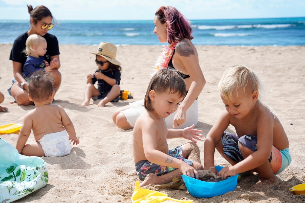 Surfing Mom’s keiki Cade Diehl, center, and Cedar Moody, far right, play while Surfing Mom’s Sachiko Stokes and Erica Diehl tend to Daniel Ritchie, Santiago Martin and Ekuale Taua’a during a Surfing Mom’s Ewa group outing Tuesday, Aug. 15, 2023, at White Plains Beach in Ewa Beach. The moms take turn surfing while other moms watch the keiki. (Kevin Fujii/Civil Beat/2023)