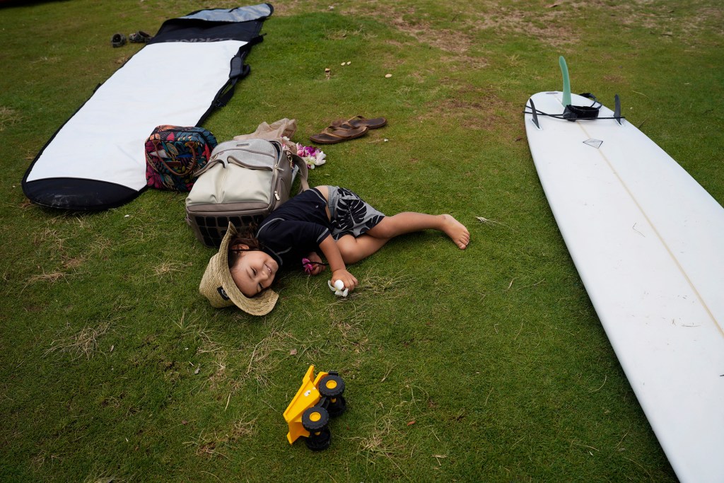 Surfing Mom’s keiki Ekuale Taua’a rolls on the grass after his mom Katelyn Taua’a returns from her surf session during the group’s weekly outing Tuesday, Aug. 15, 2023, at White Plains Beach in Ewa Beach. The moms take turn surfing while other moms watch the keiki. (Kevin Fujii/Civil Beat/2023)