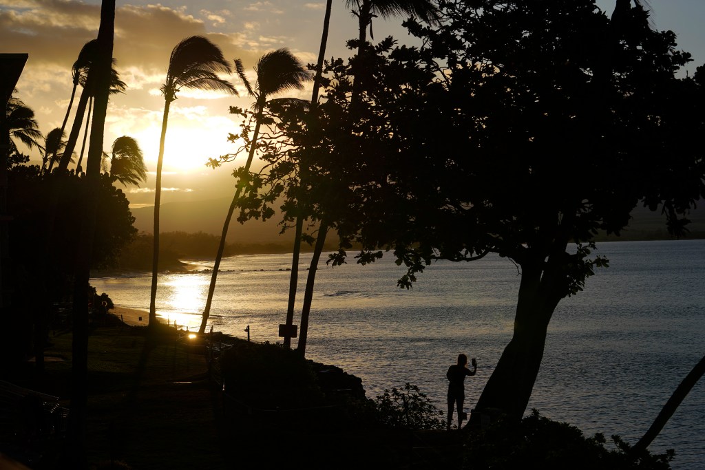 A woman photographs Maalaea Bay as the sun rises Tuesday, Aug. 22, 2023, in Maalaea. (Kevin Fujii/Civil Beat/2023)