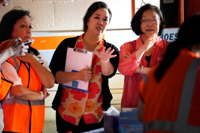 Jen Sabas, from left, Rep. Jill Tokuda and Senator Mazie Hirono stand in the dark after the power went out at the federal resource fair Saturday, Aug. 26, 2023, in Lahaina. Rep. Tokuda and Senator Hirono hosted the event. It was designed to help fire victims obtain federal assistance for important paperwork lost in the Aug. 8 fire. Sabas was the late Senator Daniel K. Inoyue’s chief of staff. (Kevin Fujii/Civil Beat/2023)