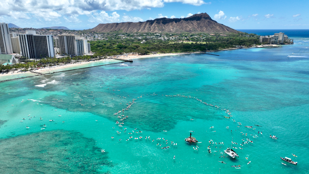 Hundreds of surfers paddled out for Lahaina on Aug. 19 off Waikiki. The event, organized by Na Kama Kai and Duke Kahanamoku Ocean Festival, was to bring community together and raise money for family and friends affected by the Maui fires. (Nathan Eagle/Civil Beat/2023)