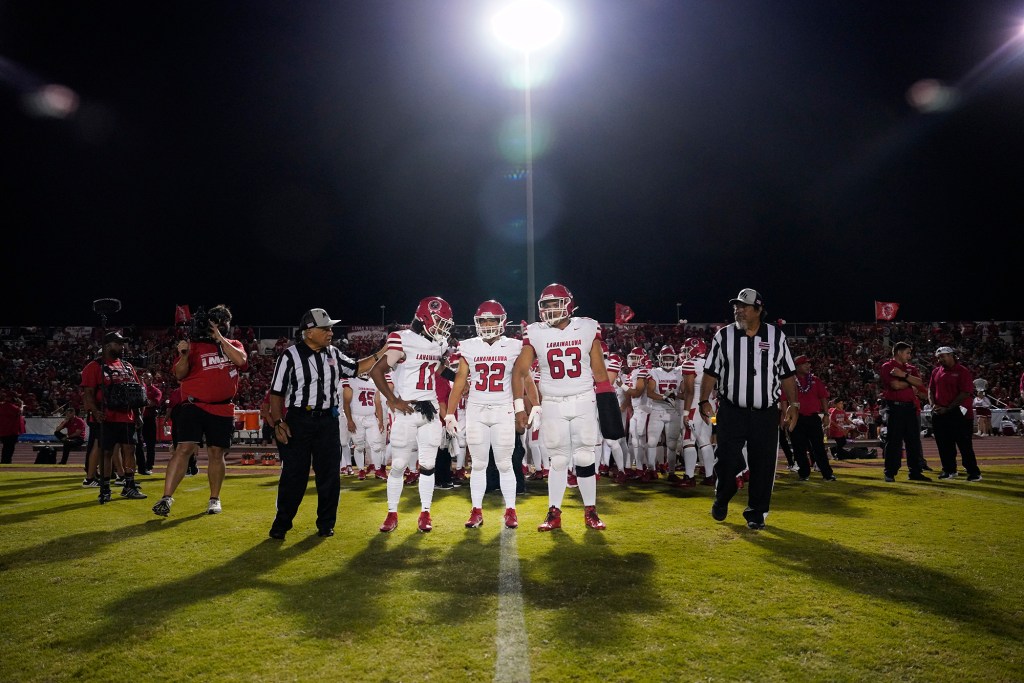 Lahainaluna High School captains Kuola Watson (11), Kaulana Tihada (32) and Morgan Montgomery (63) represent their team, school and community before playing against Baldwin High School Saturday, Sept. 30, 2023, at War Memorial Stadium in Wailuku. The sold-out game paves the little way slowly back to normalcy after the devastating Aug. 8 fire. (Kevin Fujii/Civil Beat/2023)