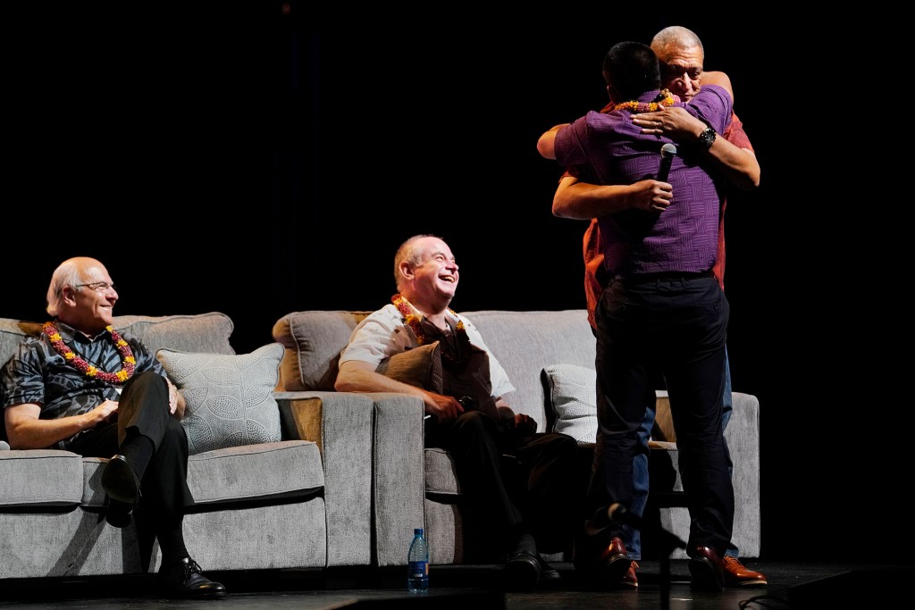 Kauai Mayor Derek Kawakami hugs Maui Mayor Richard Bissen after opening with a sentimental appreciation for the neighbor island leaders after the Aug. 8 fires Wednesday, Nov. 16, 2023, at the 22nd Native Hawaiian Convention at Maui Arts & Culture Center in Kahului. The mayors including Honolulu Mayor Richard Blangiardi, seated left, and Hawaii County Mayor Mitch Roth were part of a panel discussion Hawaii’s Mayors: A Collective Commitment to Housing.(Kevin Fujii/Civil Beat/2023)