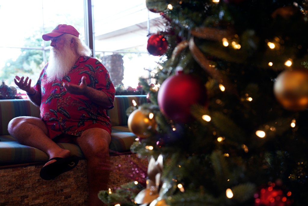Ron Proctor talks with a Civil Beat reporter at his temporary residence at the Royal Lahaina Resort. “I tell people you don’t pay me to be Santa, you pay me to wear this beard on Maui in July and August when I’m trying to play golf and I’m trying to putt and sweat is literally dripping out of my beard. It’s like having a cat on your face.” (Kevin Fujii/Civil Beat/2023)