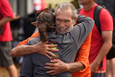 Hawaiian activist Walter Ritte, of Molokai, hugs Big Island’s Aunty Pua Case after the Hoʻūlu Lahaina Unity Walk Saturday, Jan. 20, 2024, in Lahaina. Uncle Archie Kalepa organized the Lele Aloha group to bring the diverse people of Lahaina together after the devastating Aug. 8 fire destroyed the historic West Maui town. (Kevin Fujii/Civil Beat/2024)
