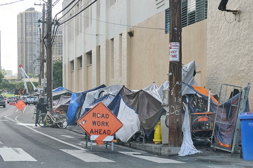An example of a homeless tent/shelter predominates the image
