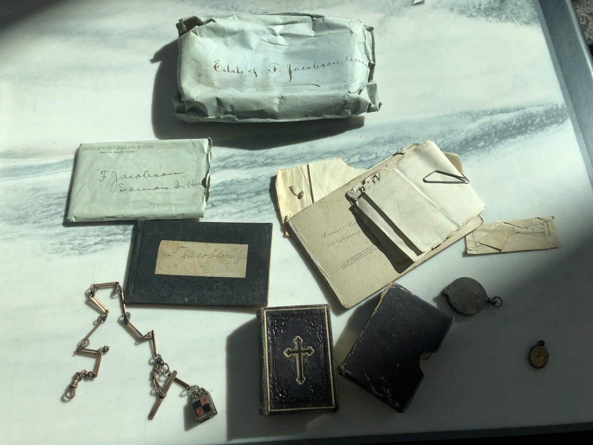 Old letters, a locket and a bible from a dead letters package laid out on a table.