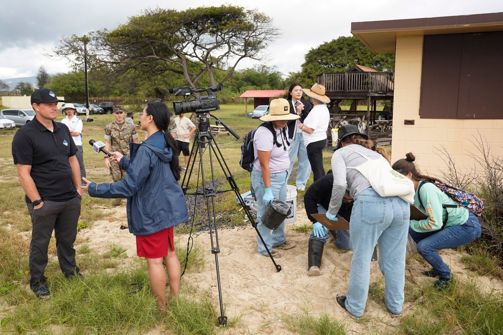 Samples are taken behind a local television news camera during an interview at Marine Corps Base Hawaii’s Puuloa Range Training Facility Wednesday, Feb. 14, 2024, in Ewa Beach. Samples will be taken from the makai side of the projectile containment berms and tested for lead and other metals. (Kevin Fujii/Civil Beat/2024)