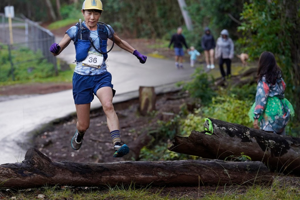 Satomi Fujimura jumps over a log during the Hawaiian Ultra Running Team’s Aiea Loop Express at Keaīwa Heiau State Recreation Area Saturday, March 23, 2024, in Aiea. Runners consider this an easy course with a distance of only 6.75-mile and 1,442’ of elevation gain. The trail is mostly wide and free of challenging obstacles. (Kevin Fujii/Civil Beat/2024)