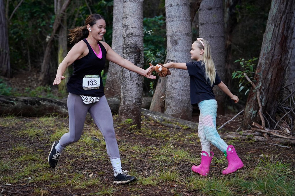 Dani Yamamoto gets a high five from her niece Gwen Yamamoto, 8, during the Hawaiian Ultra Running Team’s Aiea Loop Express at Keaīwa Heiau State Recreation Area Saturday, March 23, 2024, in Aiea. Runners consider this an easy course with a distance of only 6.75-mile and 1,442’ of elevation gain. The trail is mostly wide and free of challenging obstacles. (Kevin Fujii/Civil Beat/2024)