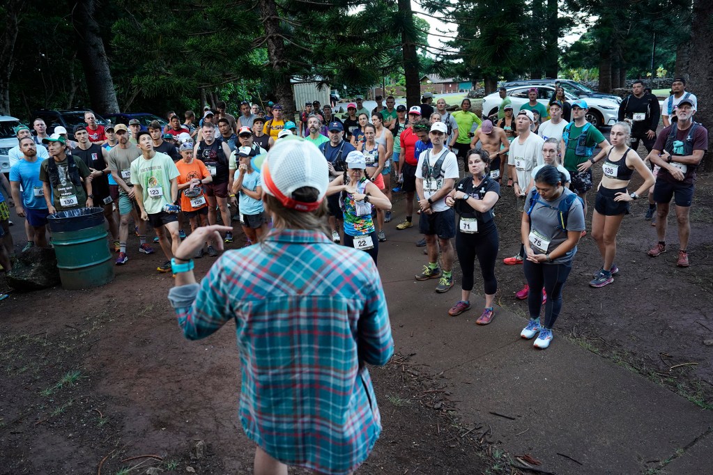 Hawaiian Ultra Running Team runners gather around Shell Barbieri Lino for instructions before kicking off their running season with the Aiea Loop Express at Keaīwa Heiau State Recreation Area Saturday, March 23, 2024, in Aiea. Runners consider this an easy course with a distance of only 6.75-mile and 1,442’ of elevation gain. The trail is mostly wide and free of challenging obstacles. (Kevin Fujii/Civil Beat/2024)