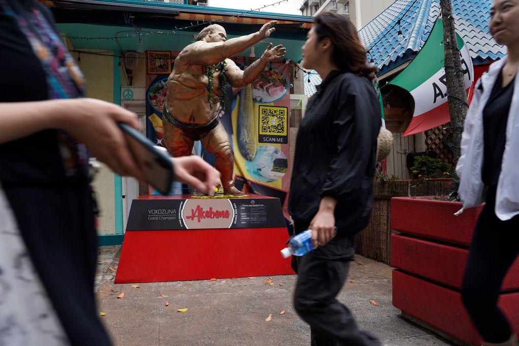 Pedestrians walk past Akebono’s full-size statue Thursday, April 11, 2024, in Honolulu. Akebono Taro passed this week at the age of 54 in Tokyo. He was the first foreign-born sumo grand champion, or “Yokozuna.” Born Chad George Ha’aheo Rowan in Hawaii, he retired in 2001, but continued to live in Japan. (Kevin Fujii/Civil Beat/2024)