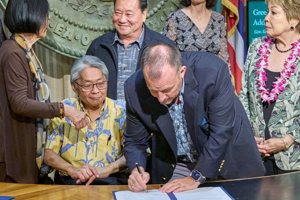 In a packed 5th floor Ceremonial Office in the Hawaii State Capital building, Governor Josh Green M.D., surrounded by State House Representatives and Senators along with members of the medical profession, signed two bills into law on Monday that aim to reduce State Income Tax and GET taxes on Medicare, Medicaid and Tricare services beginning in 2026 signaling the biggest tax cuts in Hawaii history. (David Croxford/Civil Beat/2024)