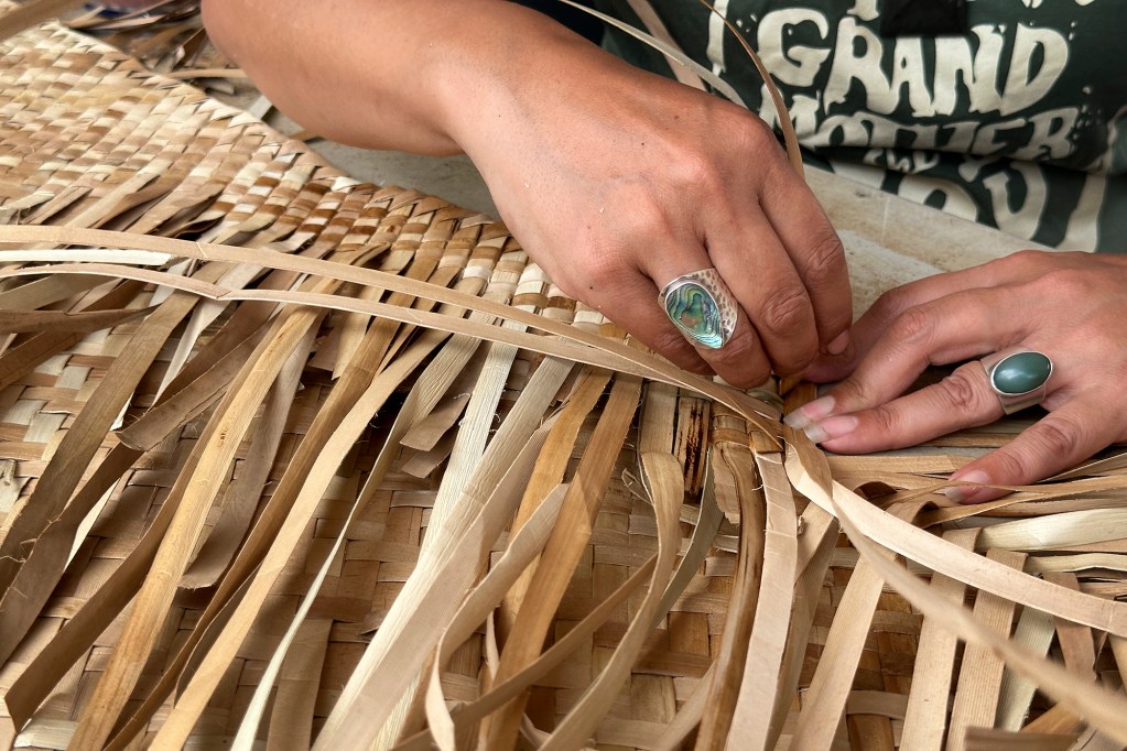 An Aotearoa woman weaves a sail Sunday, June 9, 2024, at Kualoa Regional Park in Kaneohe. The Aotearoa delegation is part of FestPac. (Kevin Fujii/Civil Beat/2024)