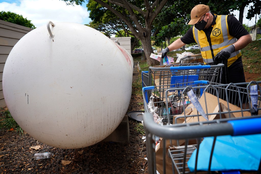 Shota Mkheidze empties rubbish from shopping carts Friday, June 21, 2024, in Kapolei. He later loaded them into his truck and will clean them with a pressure washer. (Kevin Fujii/Civil Beat/2024)