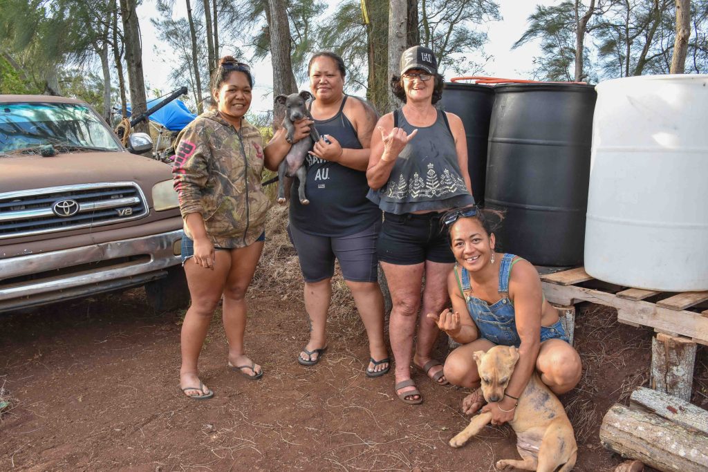 Mōʻī Kawaakoa (second to left) set up this water station on Holomua Road to help the homeless, which include her sister, Tania Kawaakoa, Tracy Shaffer and Uikihokulani Yasso. (Cammy Clark/Civil Beat/2024)