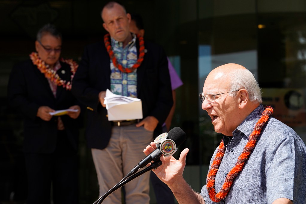 Honolulu Mayor Rick Blangiardi addresses the media during a press conference to announce new affordable housing and beds to help alleviate the homeless issue at Waikiki Vista on Friday, July 5, 2024, in Honolulu. The 19-story building will house an emergency shelter, transitional family housing and studio apartments. State Coordinator on Homelessness John Mizuno, left, and Gov. Josh Green listen in. (Kevin Fujii/Civil Beat/2024)