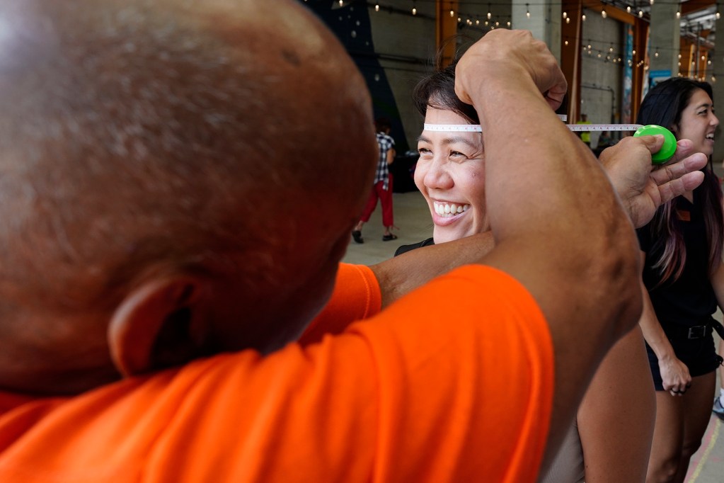 Volunteer Larry Rostrata, left of Honolulu, measures Elaine Cooper of Kaneohe for a helmet as part of Hawaii Bicycle League Smart Cycling and Bike Month 2024, HBL hosts a helmet giveaway Sunday, July 28, 2024, at SALT at Kakaako in Honolulu. (Kevin Fujii/Civil Beat/2024)