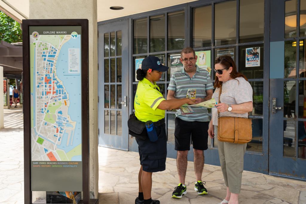 Aloha Ambassador Lani Niihau-Ashby giving Waikiki tourists directions. Until now Ambassadors have worked primarily to keep Waikiki clean, welcome tourists and give them information, and provide a safety presence but not late at night. (Courtesy: Waikiki Business Improvement District Association/2024)