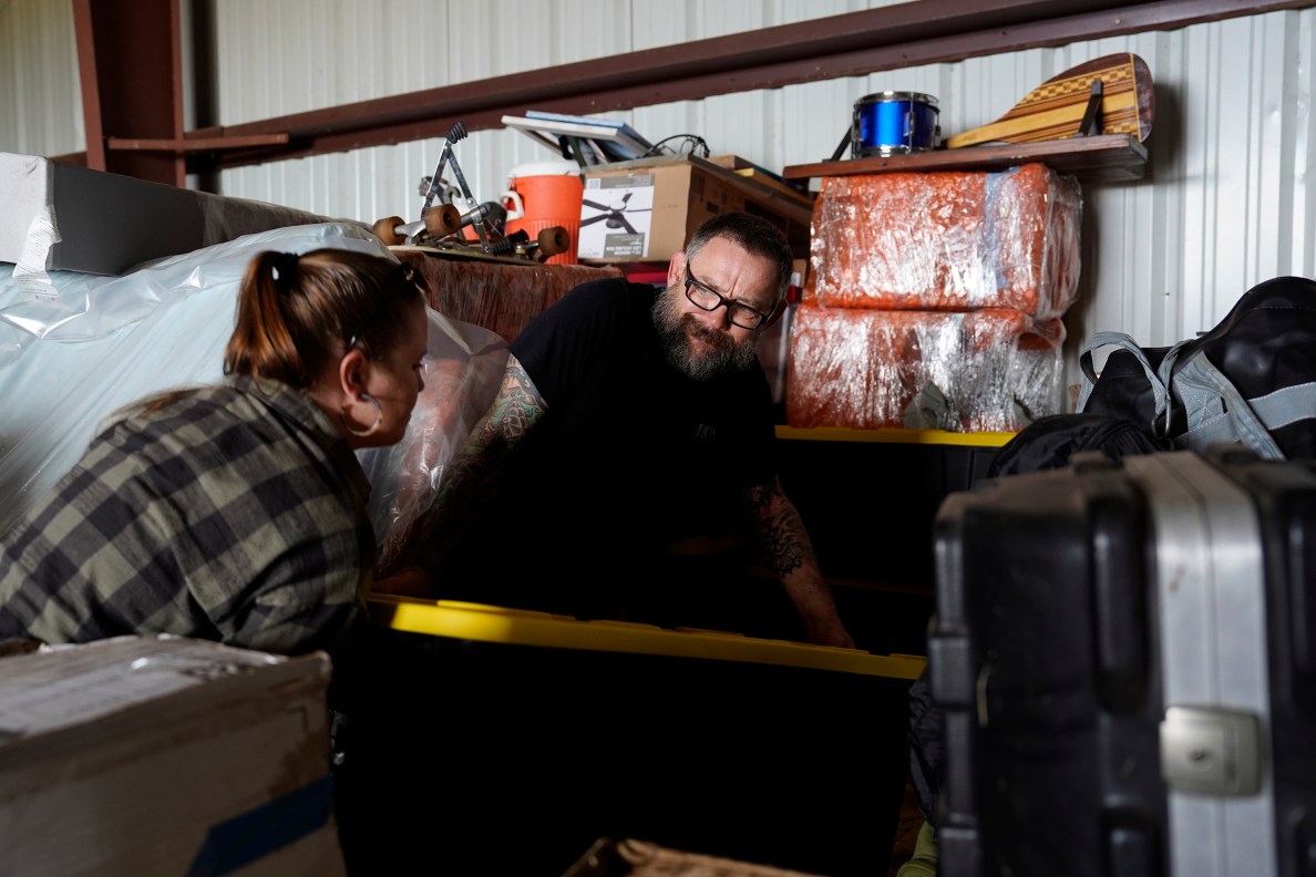 Adrienne Sunday and her husband Peter Sunday move a heavy box where they are temporarily storing their belongings Saturday, July 20, 2024, in Kula, Hawaii. The Sundays have moved numerous times and hope the struggle to find housing comes to an end after the fires on Maui. (Kevin Fujii/Civil Beat/2024)