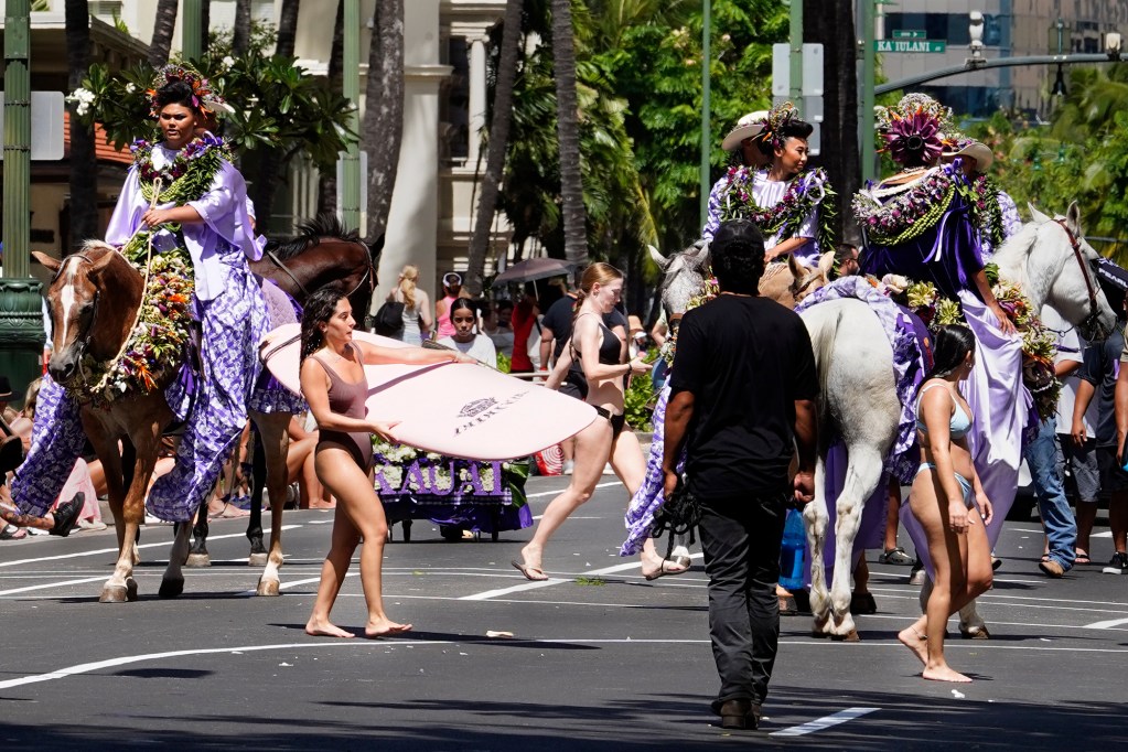 Swimmers and a surfer cut between the Princess of Kauai’s Aloha Festivals 76th Annual Floral Parade entry on Kalakaua Avenue Saturday, Sept. 25, 2024, in Honolulu. (Kevin Fujii/Civil Beat/2024)