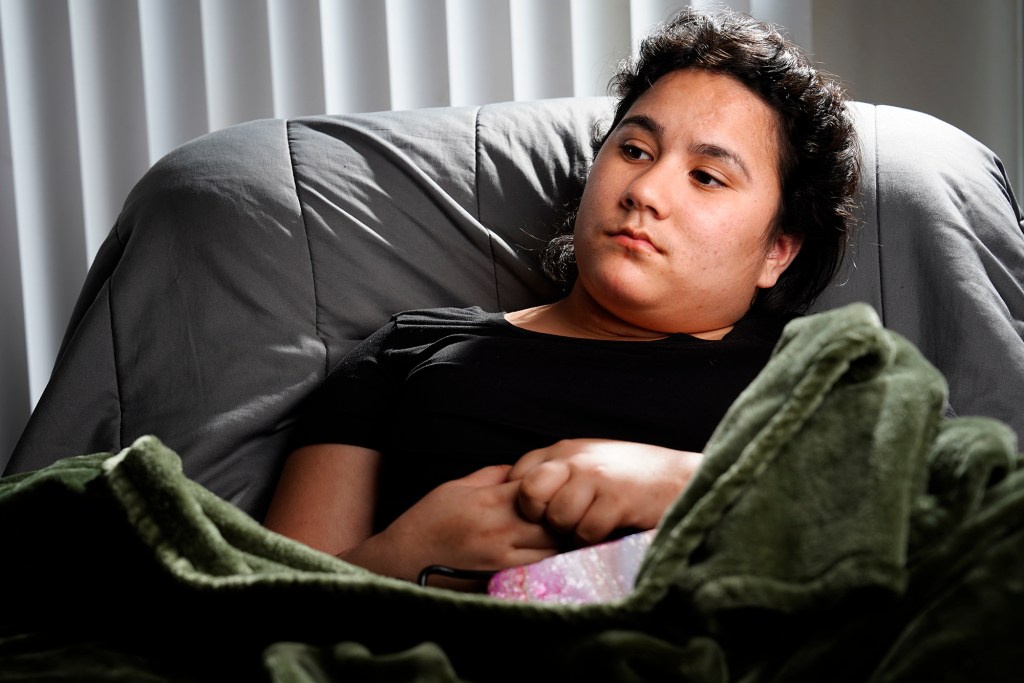 Richianna DeGuzman, 18, listens as her mother talks with a Civil Beat reporter Friday, Oct. 4, 2024, in Ewa Beach. DeGuzman was shot in the leg and head on June 17, 2023, in Maiili. Her mother says she was caught in a gunfire exchange between gangs. (Kevin Fujii/Civil Beat/2024)