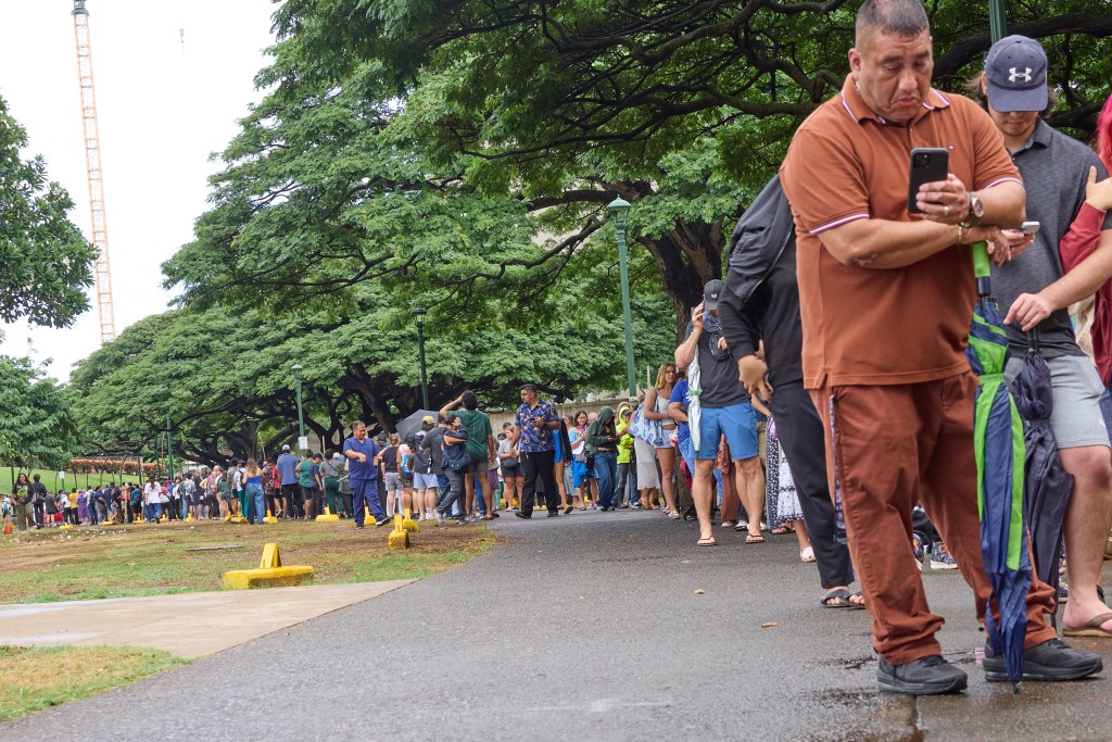 Voters at Honolulu Hale on King Street in Honolulu were met with Poll workers as they drove through the election only lane that had been set aside and coned to allow drivers to either hand off their ballots to Poll workers or drop them into several Ballot boxes placed and manned along King Street.  The lines snaked around the rear of Honolulu Hale, out to the walkway in the rear and then went all the way to Ala Wai and back providing wait times in excess of 2 hours (David Croxford/Civil Beat/2024)