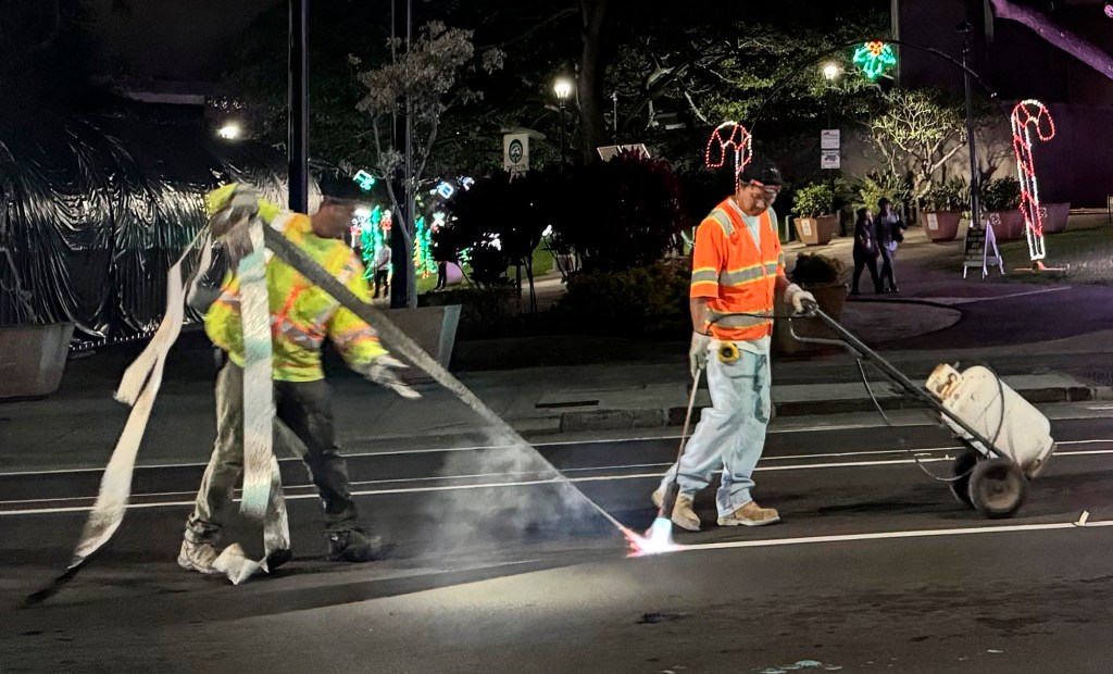Like a giant Christmas ribbon, workers Wednesday remove temporary lines on South King Street in front of the Frank Fasi Municipal Building in Honolulu. (Ben Angarone/Civil Beat/2024)