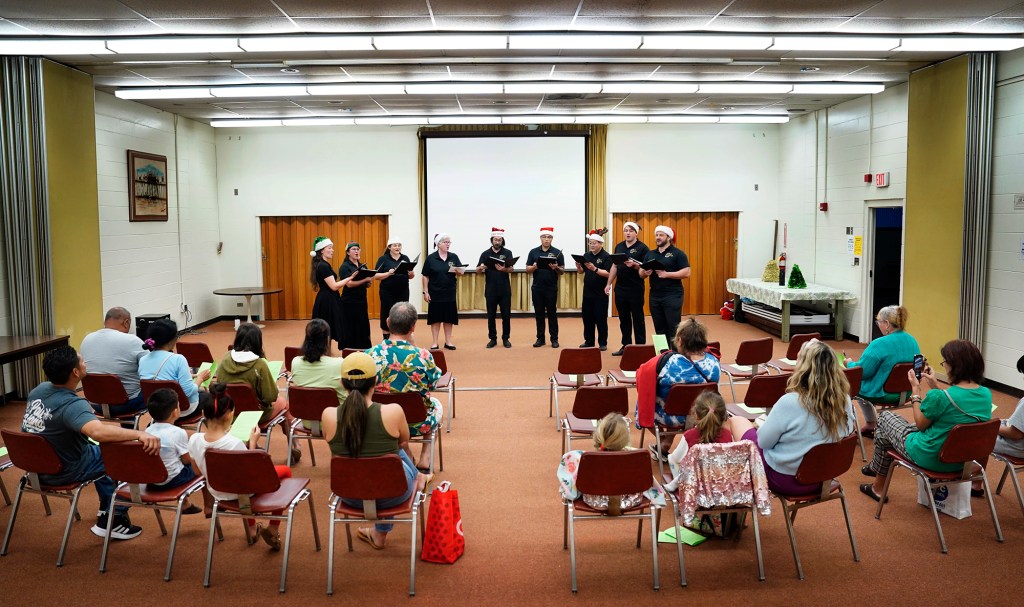 Karol’s Karolers perform Christmas carols to a small, intimate Ewa Beach Public and School Library crowd Monday, Dec. 16, 2024, in Ewa Beach. They are Brittani Alexander, from left, Deanna Patacsil, Marissa Katz, Kate Langley, Jason Nomura, Niko Sumbillo, Mitchell Moriwaki, Michal Nowicki and Karol Nowicki. (Kevin Fujii/Civil Beat/2024)
