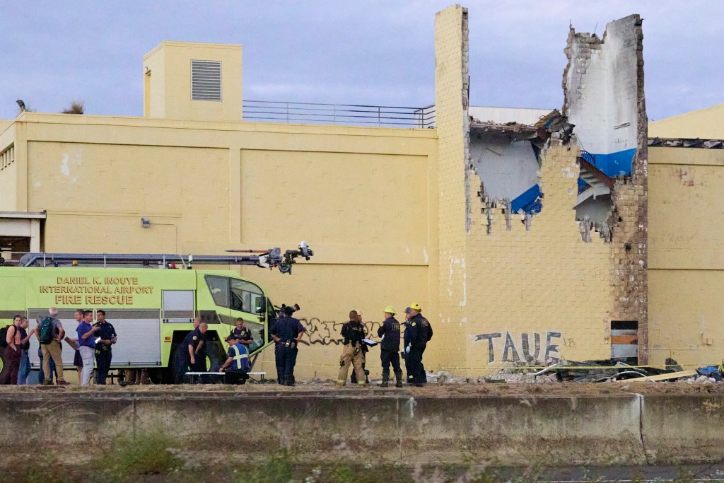 Various Agency Personnel gather at the scene of a Cessna Kamaka Air plane crash in between Aolele Street and at 3129 Ualena Street on Tuesday 12.17.24. Two pilots, believed to be on a training flight, lost control of their aircraft and it turned violently to the left and entered a rapid descent crashing into a state owned building at that address. Emergency personnel were quick to respond but unfortunately neither pilot survived. (David Croxford/Civil Beat/2024)