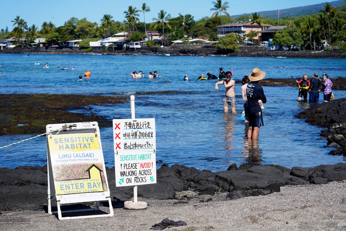 Kohala Center’s ReefTeach Education Center posts signs to protect Kahalu’u Bay Tuesday, Dec. 17, 2024,  in Kailua-Kona. Staying off the reef protects coral and its inhabitants. (Kevin Fujii/Civil Beat/2024)