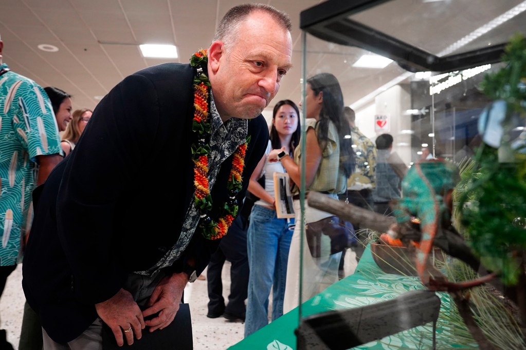 Gov. Josh Green grimaces looking at a bearded dragon after a news briefing on digitizing the Hawaiʻi Department of Agriculture’s plant and animal declarations Monday, Feb. 24, 2025, at Daniel K. Inouye International Airport in Honolulu. (Kevin Fujii/Civil Beat/2025)