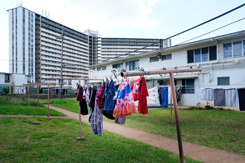 Residents’ clothes hang to dry outside their Kūhiō Park Terrace homes on Monday, Feb. 24, 2025, in Honolulu. These buildings are slated for demolition to clear land for a state housing authority tower like the one in the background. (Kevin Fujii/Civil Beat/2025)