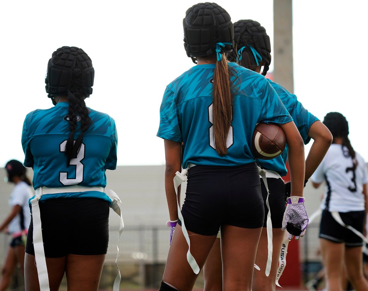 Ponytails and pigskin on the sideline of Kapolei High School’s Nia Macaraya, left #3, and Aycia Pantaleon, #8, prepare to play the first Hawai’i high school girls flag football game against Dreamhouse Nā Hōkū Tuesday, March 25, 2025, at Wai’anae High School in Wai’anae. (Kevin Fujii/Civil Beat/2025)