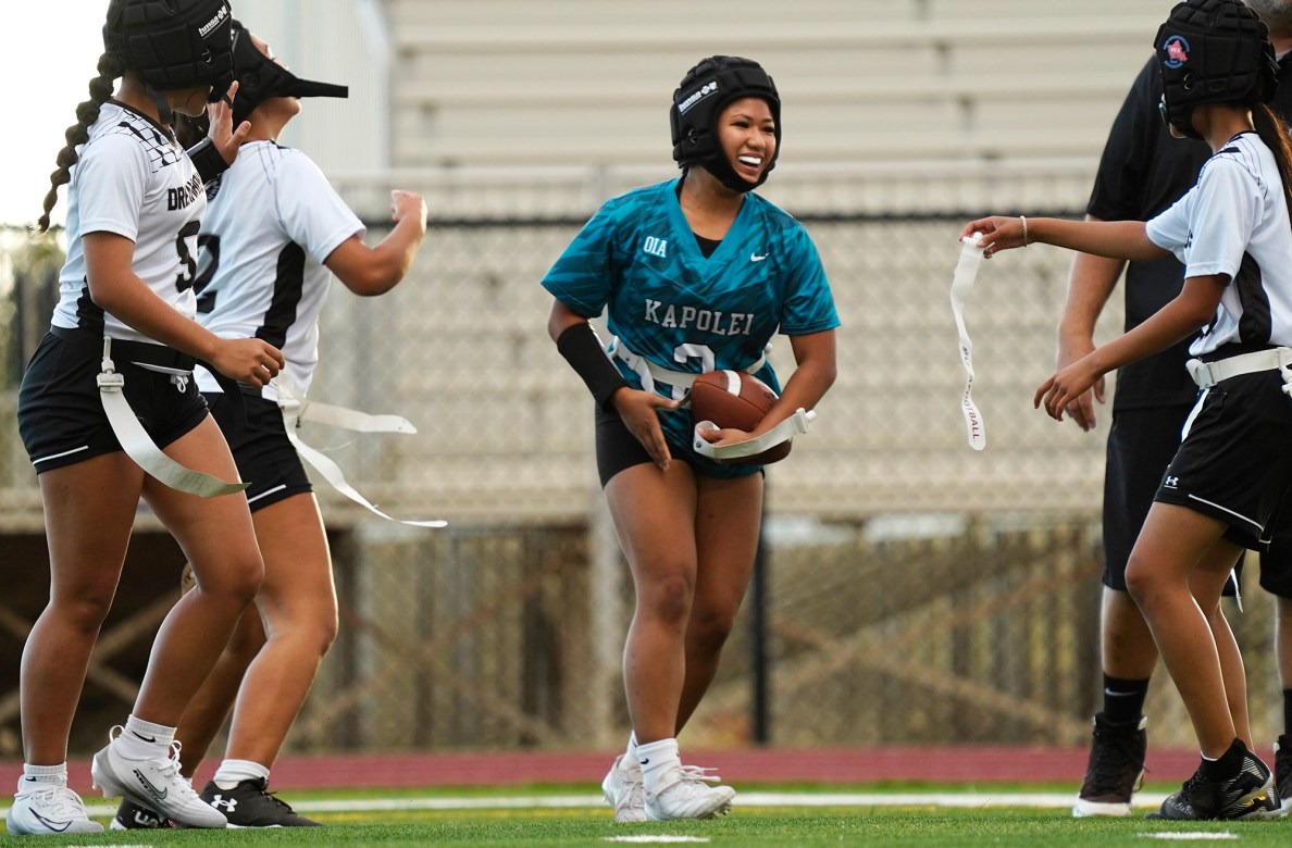 Smiles, laughter and joy mark the difference between girls flag football and the boys’ full-contact version. Players from Dreamhouse Nā Hōkū and Kapolei High School enjoy the moment after a play when Dreamhouse’s Serenity McEnroe, second left, #2, grabbed Kapolei’s Nia Macaraya’s hand to return her flag and got help off the ground as Dreamhouse’s Baily Gabaylo, right #21, returns the other flag during the first Hawai’i high school girls flag football game Tuesday, March 25, 2025, at Wai’anae High School in Wai’anae. Dreamhouse’s Anuhea Brown, left #5, pats McEnroe on the back. (Kevin Fujii/Civil Beat/2025)