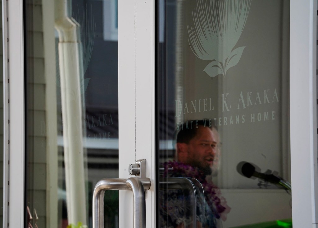 Dr. David Mattson, grandson of the late Daniel K. Akaka, is reflected on the door of the State Veterans Home which bears his grandfather’s name Wednesday, March 26, 2025, in Kapolei. (Kevin Fujii/Civil Beat/2025)